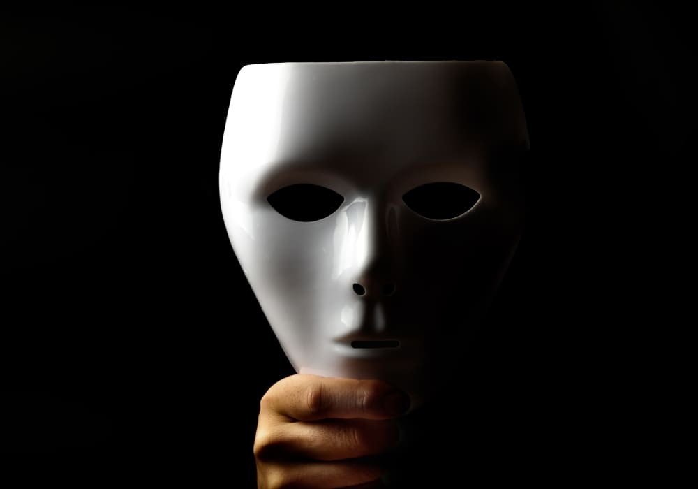 An enigmatic white mask held against a dark background, symbolizing mystery, identity, and hidden truths—perfect for exploring themes of loyalty versus proximity.