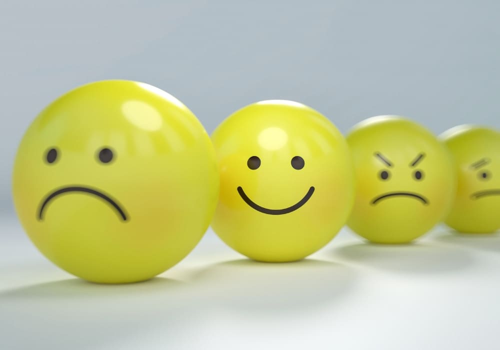 Yellow emotive faces arranged in a row, showing a progression of emotions from sadness to happiness to anger, representing the spectrum of human emotions.