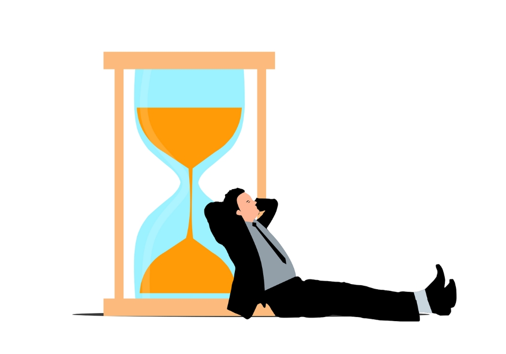 Illustration of a businessman in a suit leaning back and relaxing against a large hourglass, symbolizing the concept of quiet quitting and rethinking work-life balance.