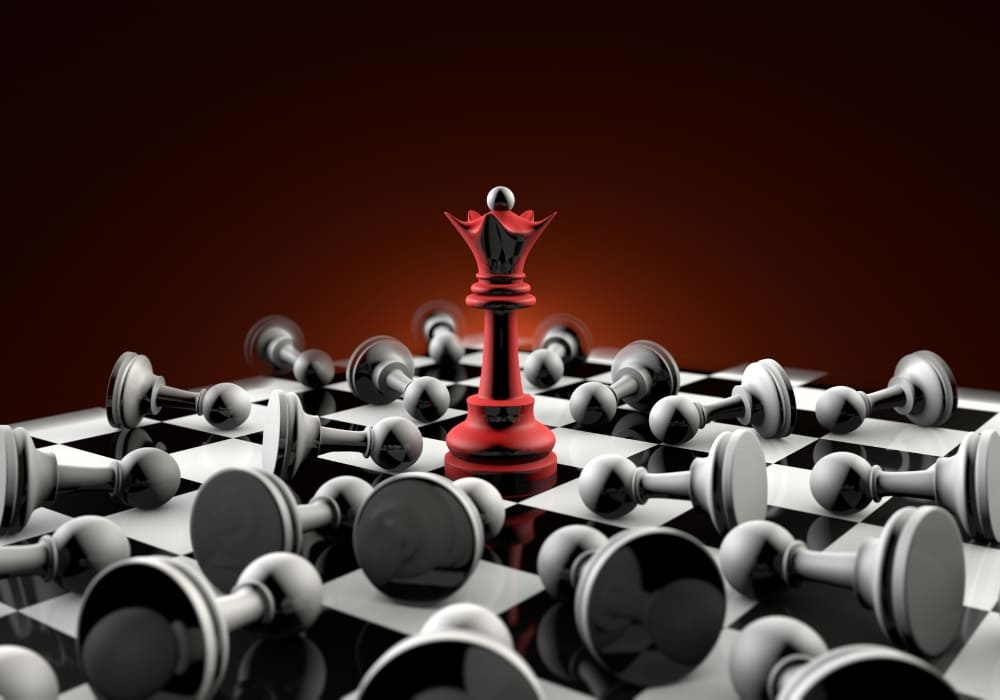 A red chess queen stands tall in the center of a chessboard, surrounded by fallen black and white pawns, symbolising dominance, strategic thinking, and victory.