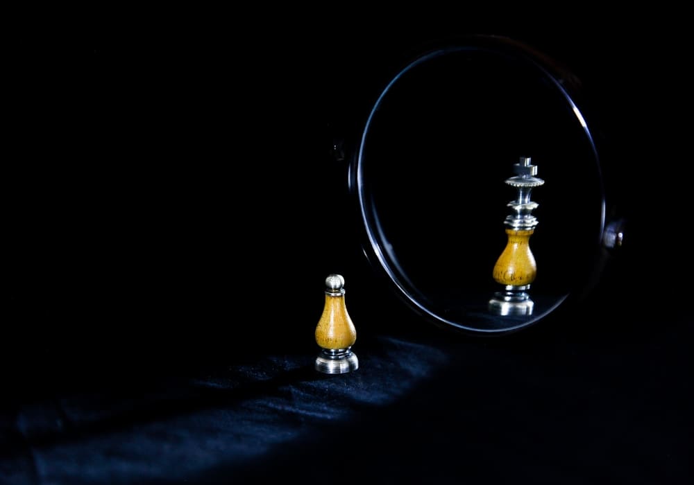 A small chess pawn reflecting as a king in a round mirror, symbolizing self-perception and ambition.