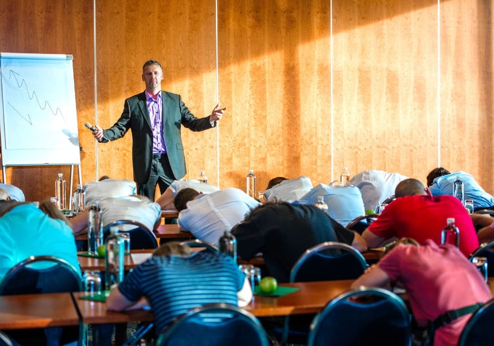 Business speaker presenting to an audience of disengaged attendees with heads down at a conference.